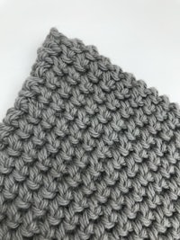 a grey crocheted beanie on a white surface