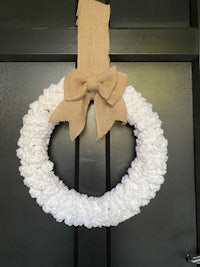 a white wreath hanging on a black door