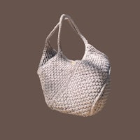 a white crocheted bag hanging on a brown background