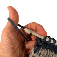 a person is holding a crochet hook in their hand