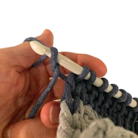 a person knitting with a crochet hook