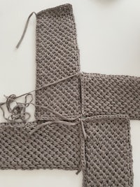 a pair of grey knitted squares on a table