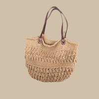 a straw bag with a leather handle on a beige background