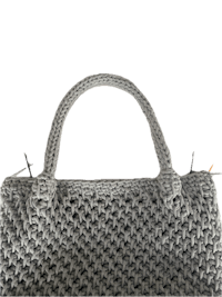 a grey crocheted handbag on a black background