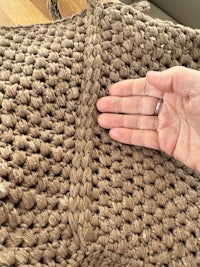 a person's hand holding a crocheted bag