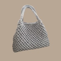 a grey crocheted bag on a beige background