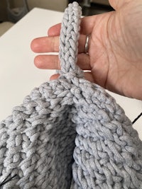 a person holding a grey crocheted bag