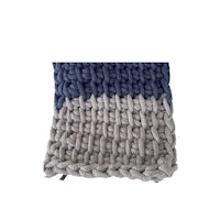 a blue and grey knitted blanket on top of a white surface