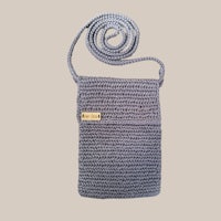 a grey crocheted crossbody bag on a beige background