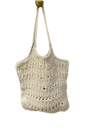 a white crocheted tote bag hanging on a hook