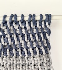 a close up of a blue and grey crocheted wall hanging